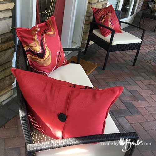 patio sofa and chair with red geode design pillows on porch