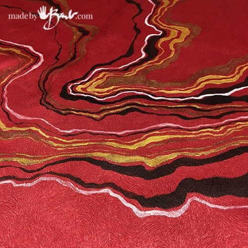 many lines of black, gold and white painted on red fabric