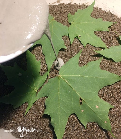 pouring concrete over the leaves and sand mound